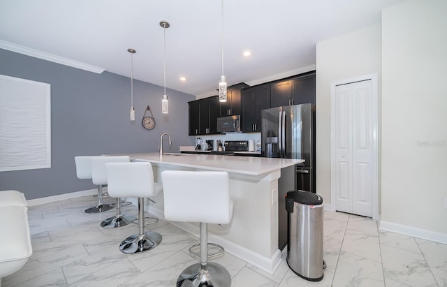 kitchen with a breakfast bar, stainless steel appliances, decorative light fixtures, and a kitchen island with sink