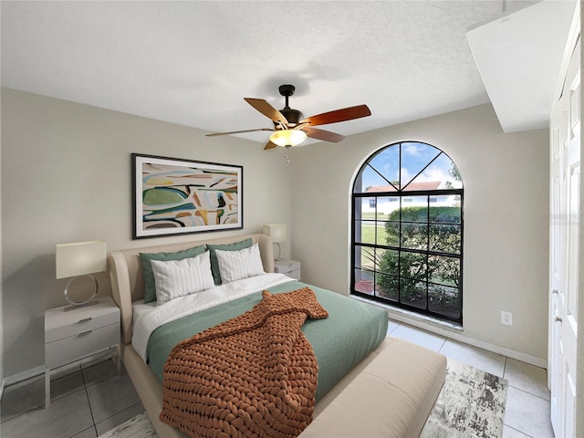 bedroom with ceiling fan, a textured ceiling, and light tile floors