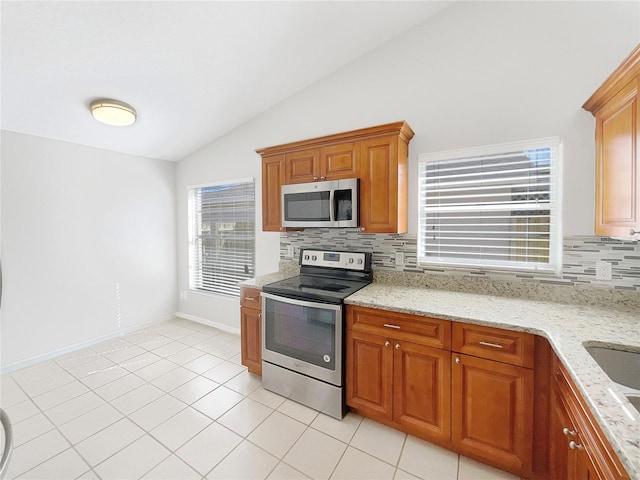 kitchen featuring tasteful backsplash, lofted ceiling, stainless steel appliances, and plenty of natural light