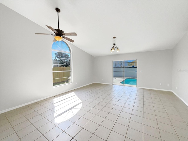 tiled spare room with vaulted ceiling and ceiling fan with notable chandelier