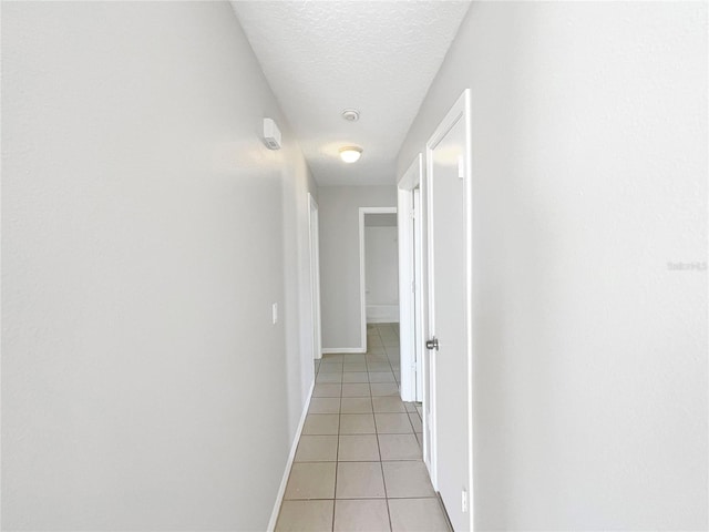 corridor featuring light tile floors and a textured ceiling