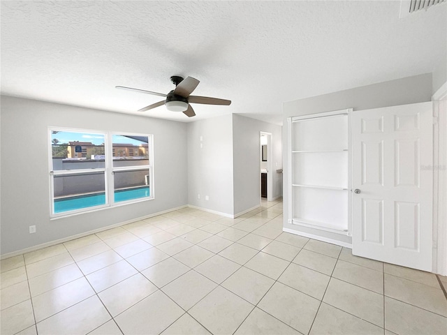 unfurnished room with ceiling fan, light tile floors, and a textured ceiling