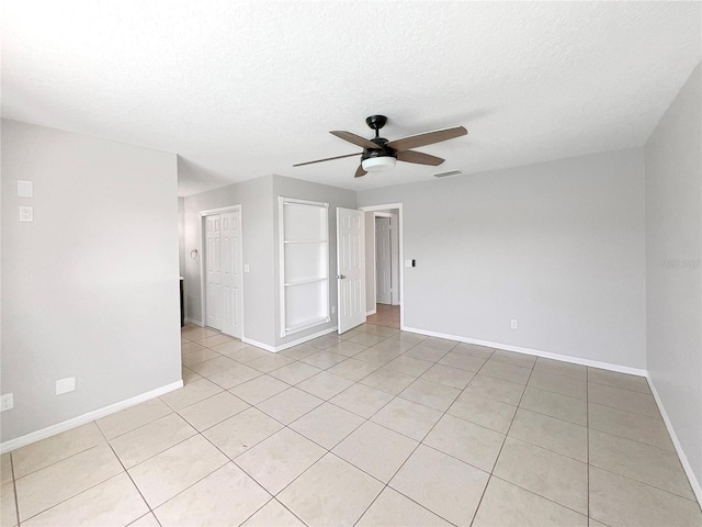 tiled spare room featuring a textured ceiling and ceiling fan