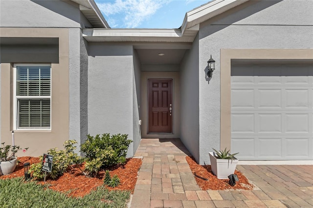 687 Campo Ln, Davenport, FL 33837 - view of exterior entry with stucco siding and a garage
