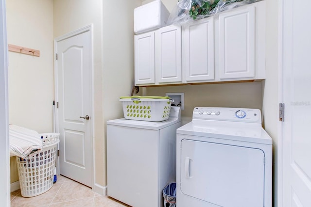 clothes washing area featuring cabinets, light tile floors, washer hookup, and washing machine and clothes dryer