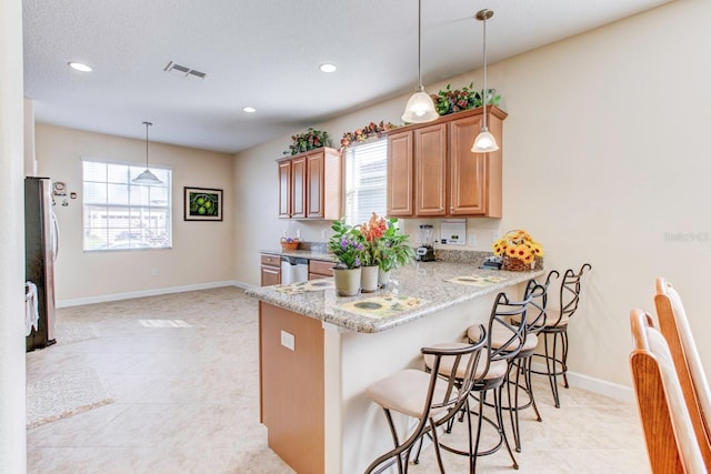 kitchen with a healthy amount of sunlight, stainless steel appliances, light tile floors, and decorative light fixtures