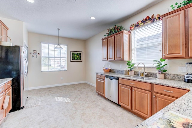 kitchen featuring hanging light fixtures, stainless steel appliances, light stone counters, sink, and light tile floors