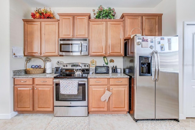 kitchen with appliances with stainless steel finishes, light tile floors, and light stone countertops