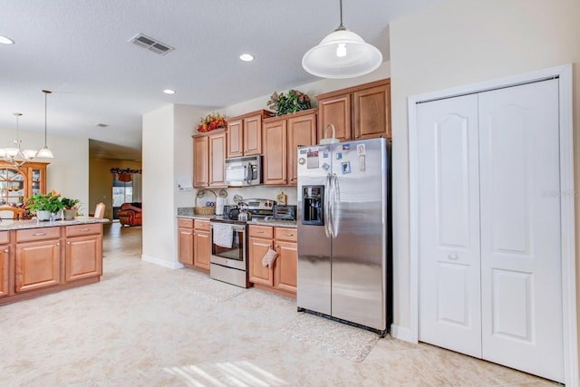 kitchen featuring appliances with stainless steel finishes, light tile floors, pendant lighting, and light stone countertops