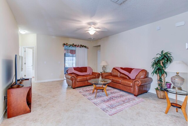 living room featuring ceiling fan, a textured ceiling, and light tile flooring