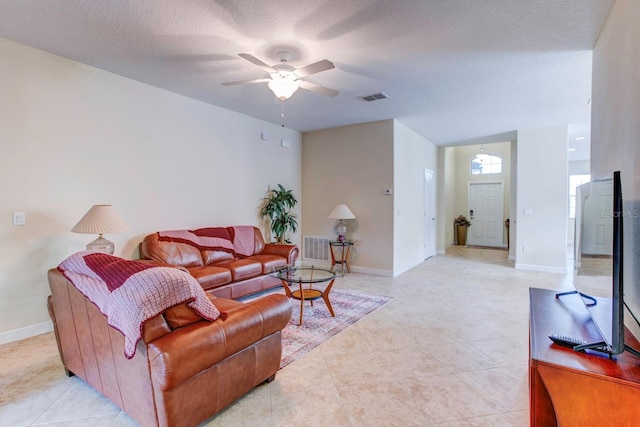 living room featuring a textured ceiling, ceiling fan, and light tile floors