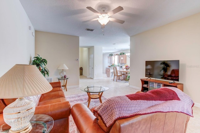 living room featuring light tile floors, ceiling fan, and a textured ceiling