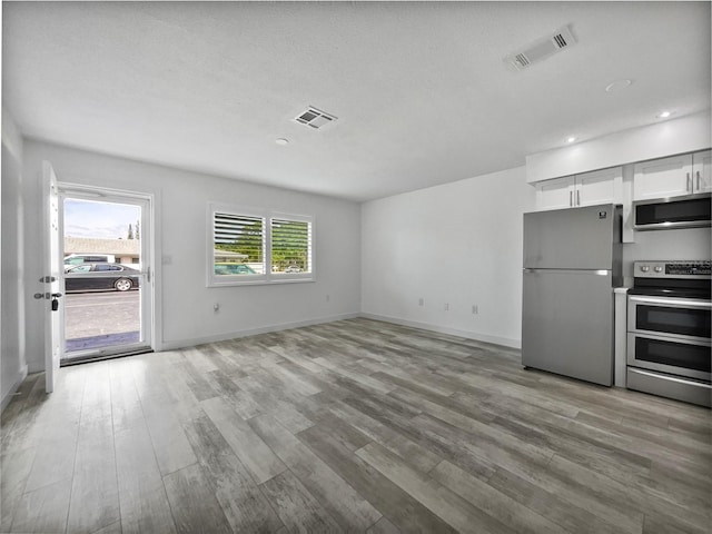 kitchen featuring a textured ceiling, light hardwood / wood-style floors, stainless steel appliances, and white cabinetry