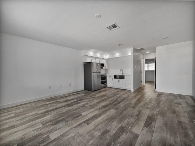 unfurnished living room with sink and hardwood / wood-style floors