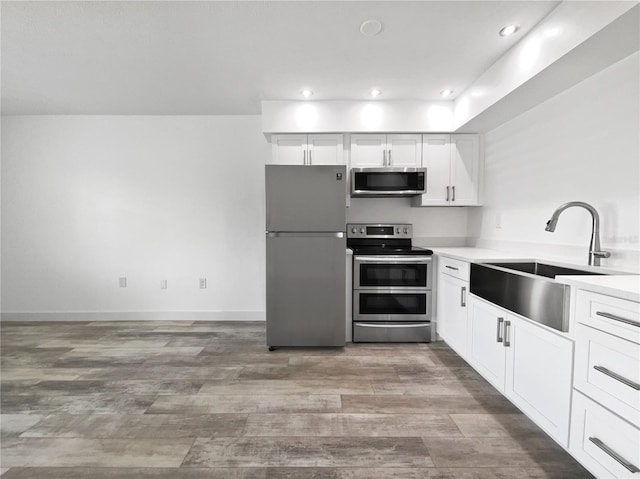 kitchen with sink, stainless steel appliances, light wood-type flooring, and white cabinetry