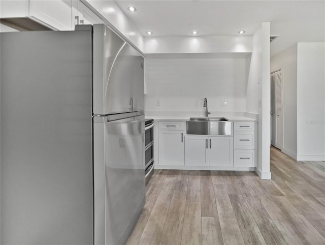 kitchen with stainless steel appliances, light wood-type flooring, and white cabinets