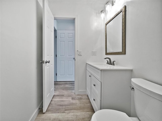 bathroom with wood-type flooring, toilet, and vanity with extensive cabinet space