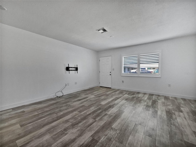 spare room featuring a textured ceiling and dark hardwood / wood-style floors