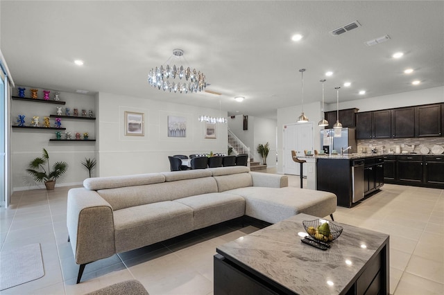 living room with a notable chandelier, light tile floors, and sink