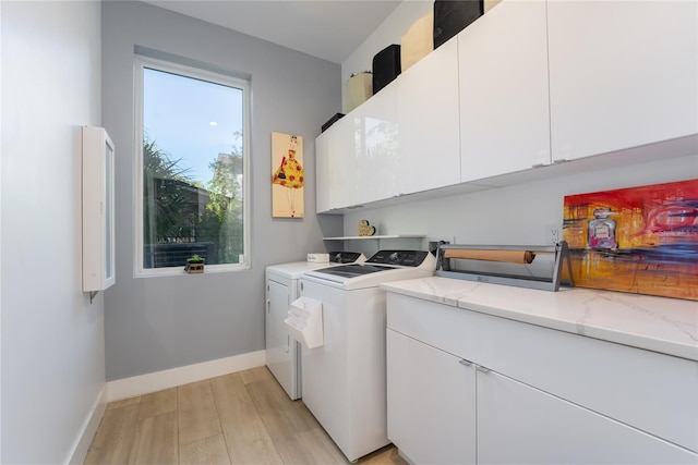 laundry area featuring light wood-type flooring, cabinets, and washer and dryer