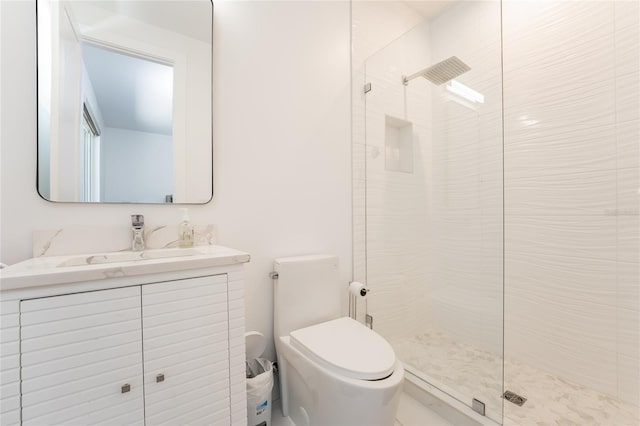 bathroom with toilet, vanity, and a tile shower