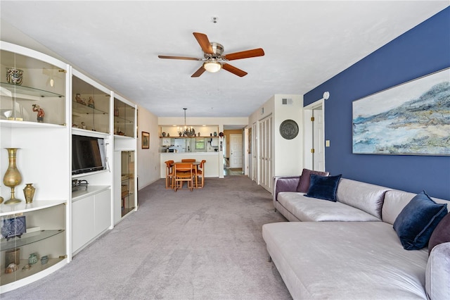 carpeted living room with ceiling fan with notable chandelier