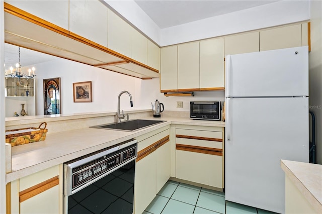 kitchen with dishwashing machine, white refrigerator, sink, cream cabinetry, and hanging light fixtures