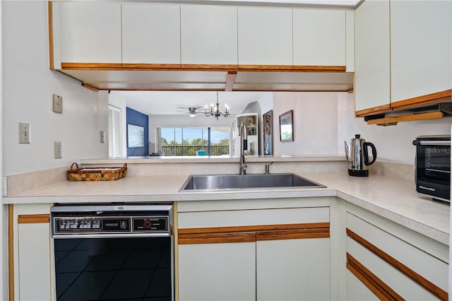 kitchen with hanging light fixtures, sink, white cabinetry, a chandelier, and black dishwasher
