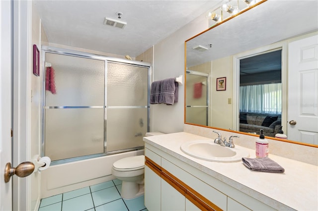 full bathroom featuring shower / bath combination with glass door, toilet, tile floors, and vanity with extensive cabinet space