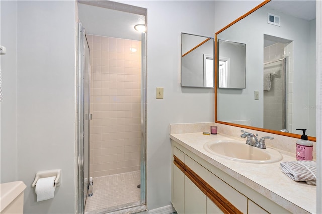 bathroom featuring toilet, large vanity, and a shower with door