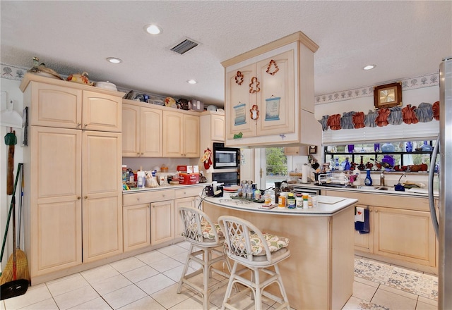 kitchen featuring light tile floors, a kitchen island, a textured ceiling, a breakfast bar, and black microwave