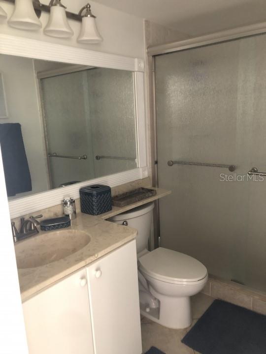 bathroom featuring an enclosed shower, toilet, and large vanity