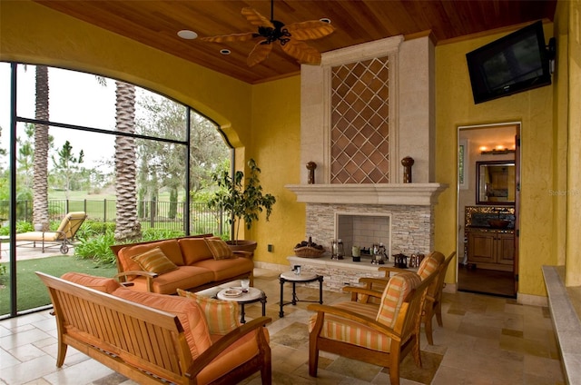 sunroom featuring wood ceiling, ceiling fan, and a fireplace