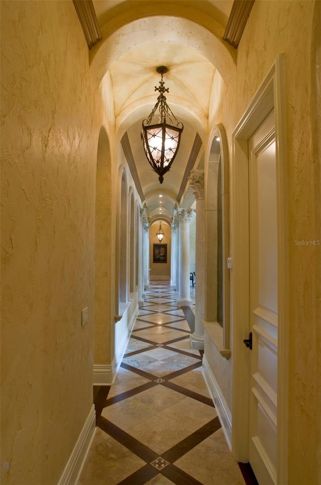 hall featuring decorative columns and tile flooring