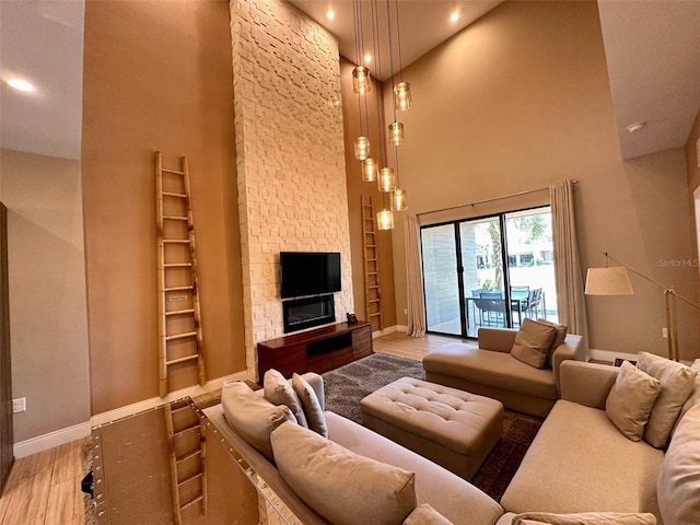 living room with a towering ceiling, light hardwood / wood-style flooring, and a fireplace