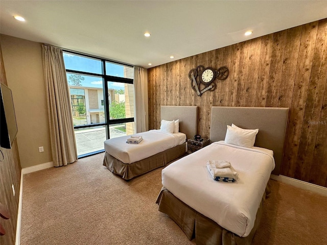 bedroom featuring access to exterior, light colored carpet, wood walls, and expansive windows