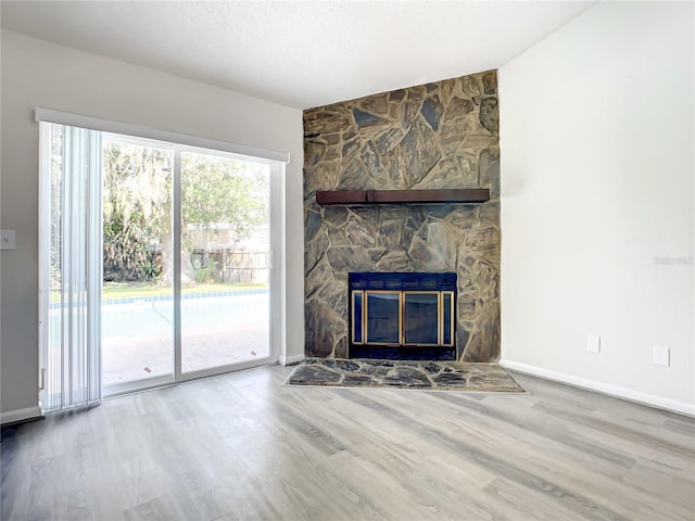 unfurnished living room with a fireplace, baseboards, and wood finished floors