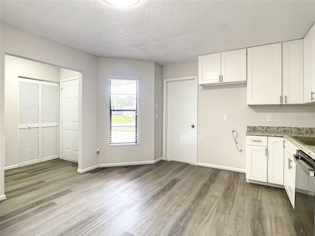 kitchen with light wood-type flooring, baseboards, white cabinetry, and stainless steel dishwasher