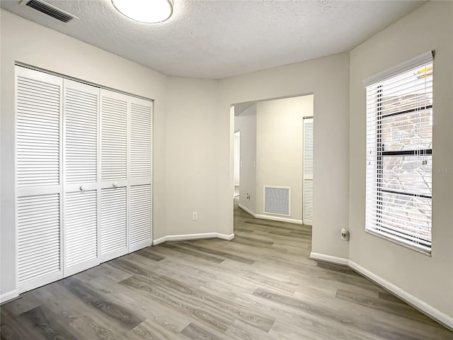 unfurnished bedroom with light wood-style flooring, a closet, and visible vents