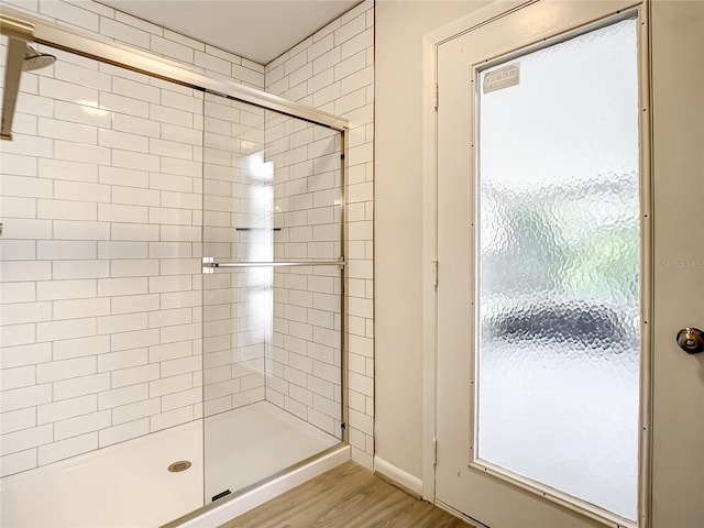 bathroom with a tile shower and wood finished floors