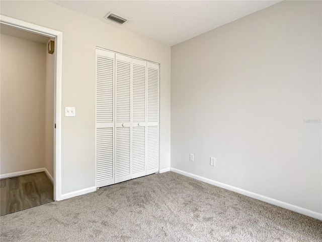 unfurnished bedroom featuring carpet, a closet, visible vents, and baseboards