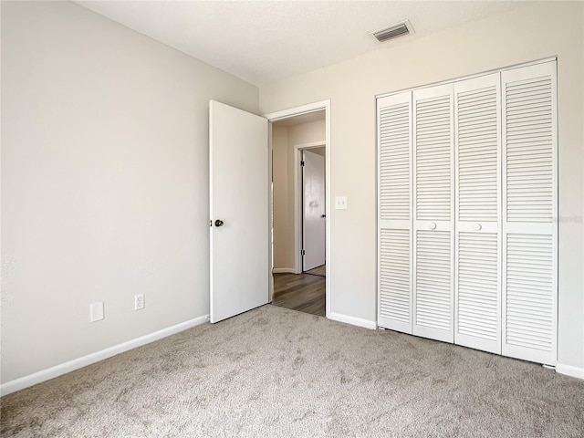 unfurnished bedroom with carpet floors, a closet, visible vents, and baseboards