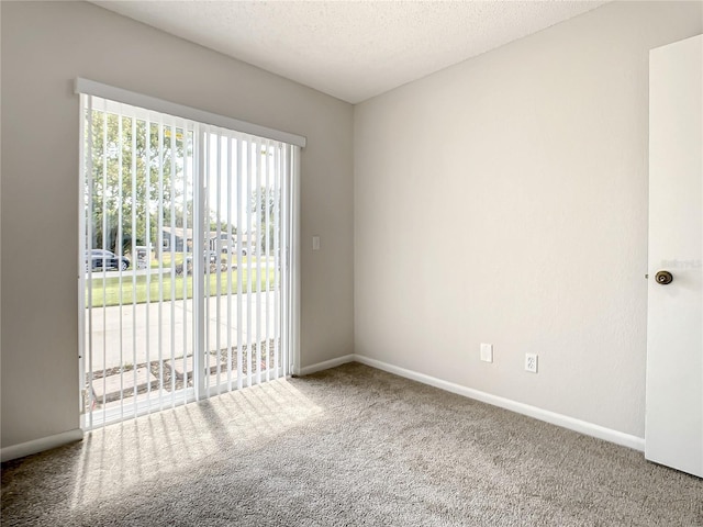 carpeted empty room featuring a textured ceiling and baseboards