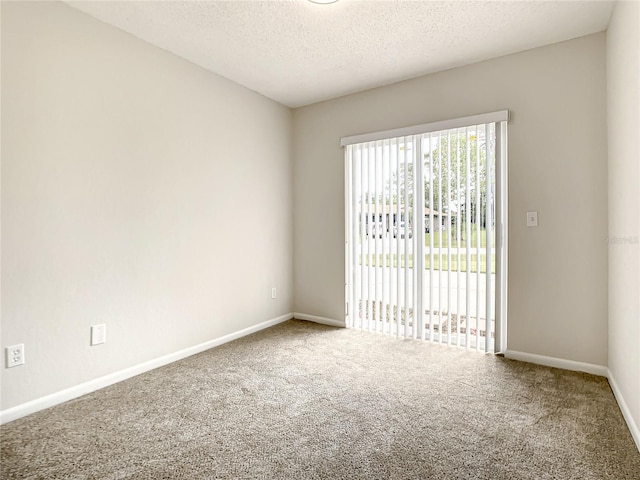 carpeted spare room with a textured ceiling and baseboards