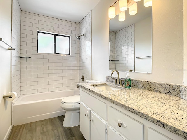 bathroom with toilet, vanity, wood finished floors, and shower / bathing tub combination