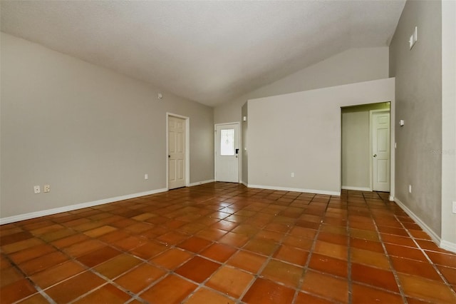 unfurnished room featuring dark tile floors and lofted ceiling