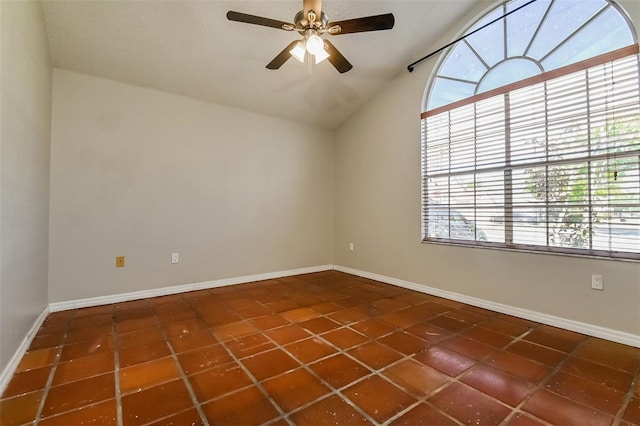 tiled empty room with ceiling fan, vaulted ceiling, and a textured ceiling