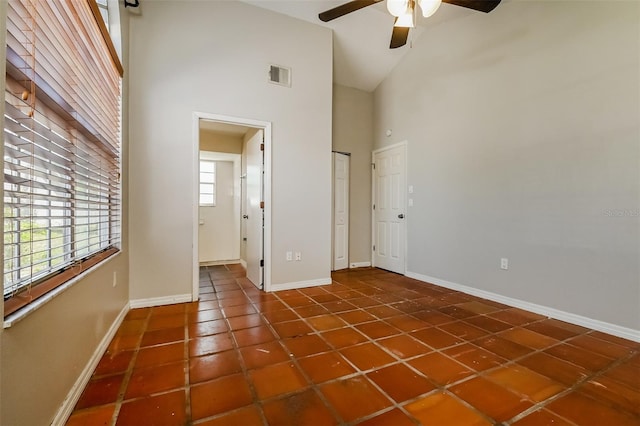 unfurnished room featuring dark tile floors, ceiling fan, and high vaulted ceiling