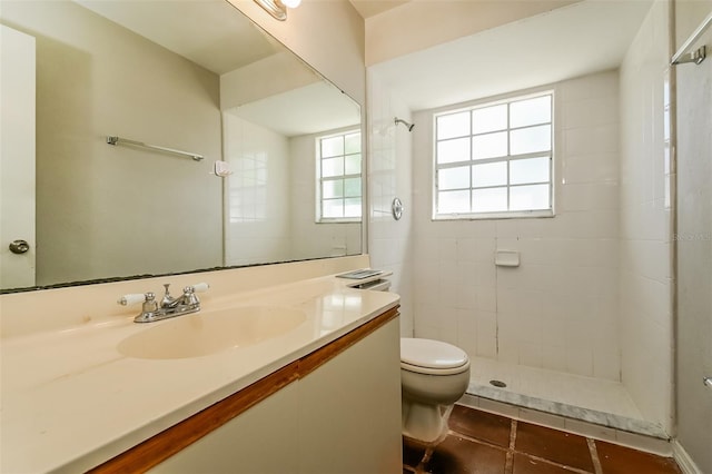 bathroom with tile floors, toilet, tiled shower, and vanity