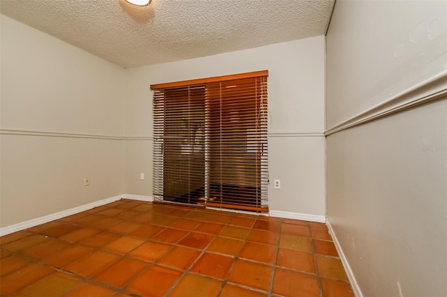 spare room with a textured ceiling and tile floors